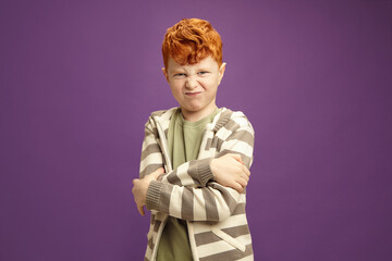 Portrait of Displeased and Angry Redhead Boy Crossing Arms Standing on Violet Isolated
