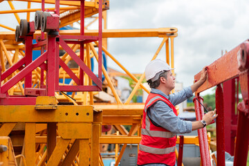 Crane foreman uses walkie-talkie and inspect the construction crane lifting heavy items in the storage warehouse for assembly on the construction site