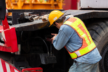Engineers and technicians grease the wheel axle of a large crane before moving to the construction...
