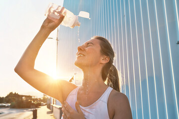 Athletic Woman Drinks water and Splashes Water on Her Face After Intense Exercise, Post-Run Refreshment, Summer Fitness Hydrating and Cooling Off During a Hot Day Run