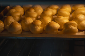 A close up of homemade choux cream baking in the oven, concept of bakery recipe, kitchen and...