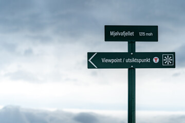 Fototapeta premium Sign of reaching Mjolvafjellet mountain with viewpoint over Andalsnes. with mountains and snow and clouds in the background
