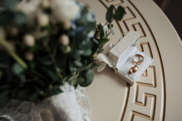 A bouquet of flowers sits on a table next to a white box containing two rings. Concept of love and commitment, as the rings symbolize a promise to be together forever