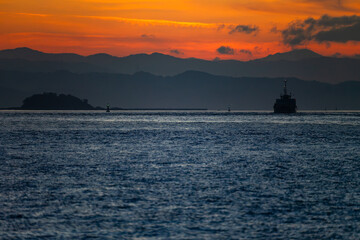 朝焼けの関門海峡の満珠島と船のシルエット20240721