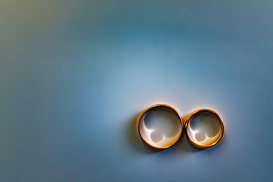 Engagement rings with spectacular sunlight shadows on blue background. Soft focus, blurring. copy space, text space, template, layout, mockup