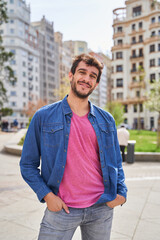 vertical portrait of a happy young man on a city street looking at the camera.