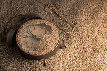 Vintage pocket watch and key on the sand. Retro style.