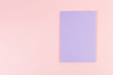 Top view of purple notebook on pink background. School, office wallpaper. Flat lay, copy space.