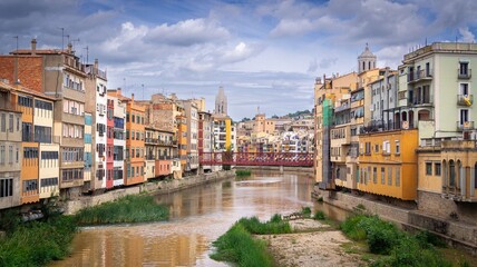 Colorful buildings along the Onyar River in Girona, Spain with a cloudy sky