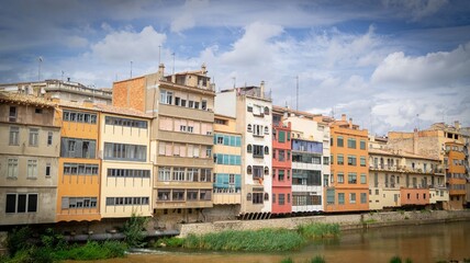 Colorful buildings along the Onyar River in Girona, Spain under a cloudy sky