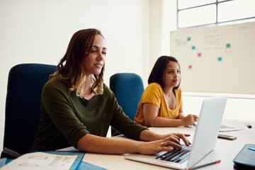 Meeting, typing and business people with laptop in office for teamwork, project development or proposal review. Consulting agency, report and employees at desk for collaboration, planning or feedback