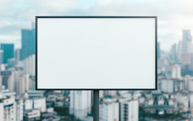 Fototapeta premium Large blank billboard on rooftop with blurred modern cityscape background, ideal for advertising and commercial use.