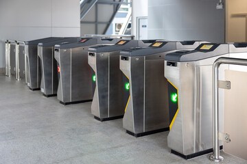 A row of electronic turnstiles are lined up on a gray floor