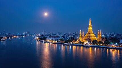 Fototapeta premium Stunning view of a city skyline at night, featuring a golden temple by a river under a bright moon, creating a serene atmosphere. Bangkok Thailand.