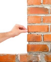 Obraz premium hand placing a brick on a compound wall, isolated in white 
