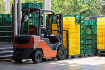 A forklift is driving through a warehouse full of green and yellow boxes