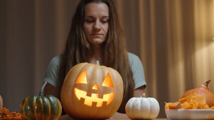 A Family Evening in a Cozy Home Setting, a Woman Shows a Newly Carved Jack-O'-Lantern for Halloween. Pumpkins on the Table.