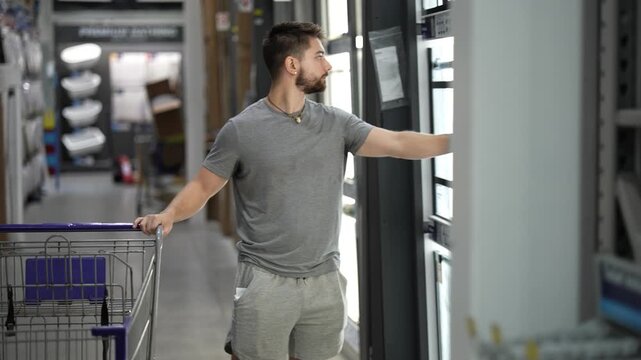 Young man pushing shopping cart in the home improvement hardware store in the bathroom accessories department.
