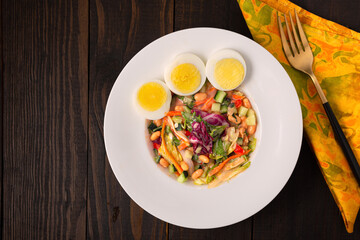 Overhead view of West African vegetable soup with boiled eggs in a white bowl on a wooden surface; copy space