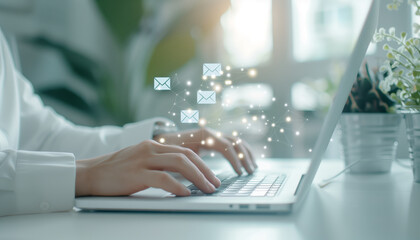 Close-up of hands typing on a laptop, with email icons floating above, symbolizing digital communication and productivity.
