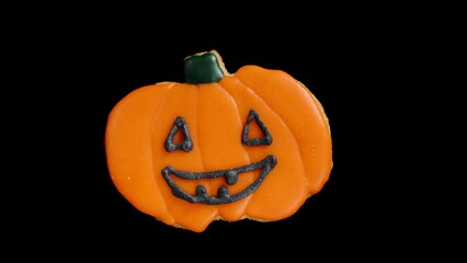 Gingerbread Cookie Shaped Like a Jack-o'-Lantern Painted with Sugar Icing, Black Background, Holiday Theme.