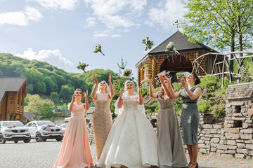 A group of women are standing outside, with one of them holding a bouquet of flowers. The women are...