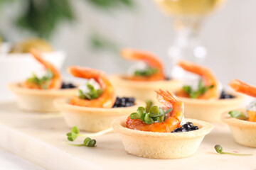 Delicious canapes with shrimps and black caviar on table, closeup