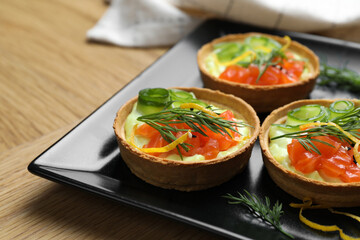 Delicious canapes with salmon on wooden table, closeup