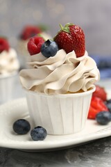 Tasty cupcake with different berries on light grey table, closeup