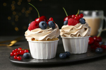 Tasty cupcakes with different berries on grey table, closeup