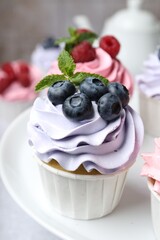 Tasty cupcakes with different berries on table, closeup
