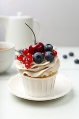 Tasty cupcake with different berries and tea on white marble table