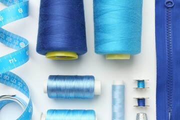 Flat lay composition with different sewing supplies on white background