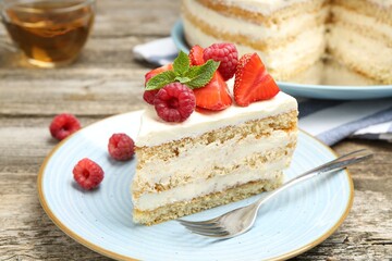 Piece of tasty sponge cake with fresh berries and mint served on wooden table, closeup