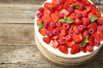 Tasty sponge cake with fresh berries and mint on wooden table, above view. Space for text