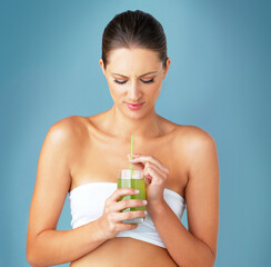 Fototapeta premium Woman, green smoothie and unhappy detox in studio, weight loss beverage and blue background. Female person, laugh and organic juice or raw shake for nutrition, vitamin and vegan supplement for health