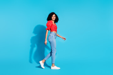 Full body profile portrait of gorgeous young woman walk empty space wear top isolated on blue color background