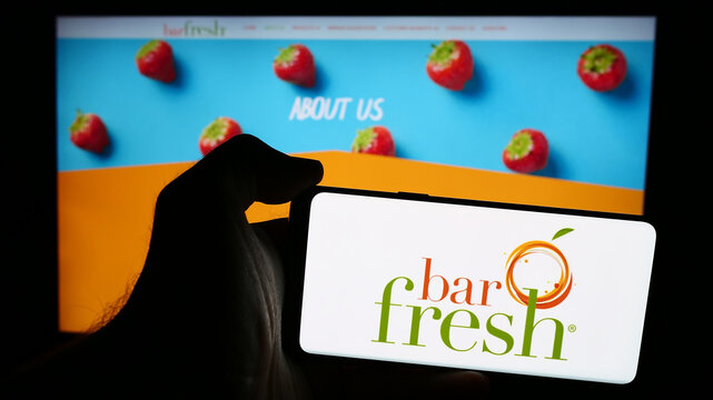 Stuttgart, Germany - 07-16-2024: Person holding mobile phone with logo of American beverage company Barfresh Food Group Inc. (BRFH) in front of web page. Focus on phone display.