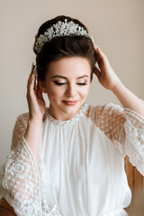 A woman wearing a white dress and a tiara. She is smiling and looking at the camera