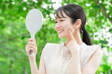 新緑の中で鏡を見る女性