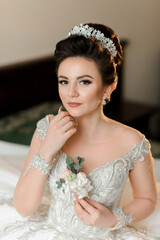 A woman wearing a tiara and holding a flower in her hand. She is dressed in a white gown and is...