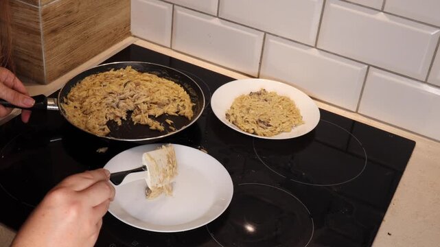 The process of preparing mushroom dishes. A woman serves pasta risoni with mushroom sauce on a white plate.