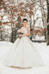 A woman in a white dress is standing in the snow with a bouquet of flowers in her hand