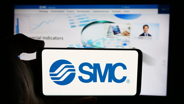 Stuttgart, Germany - 07-25-2024: Person holding cellphone with logo of Japanese machinery company SMC Corporation in front of business webpage. Focus on phone display.