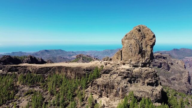Aerial view of people hiking in Gran Canaria at Roque Nublo mountain geologic rock formation. Drone view of Teide and Tejeda in the background