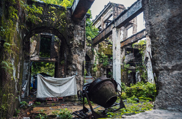 Overgrown concrete structure with cement mixer in the ruins of a building