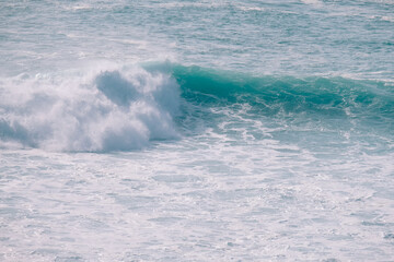 A large ocean wave crashing powerfully against the shore, showcasing the force and dynamic nature of the sea.