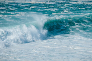 A close-up of a powerful ocean wave breaking, highlighting the raw force and beauty of the sea in motion.