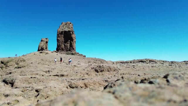Aerial view of people hiking in Gran Canaria at Roque Nublo mountain geologic rock formation. Drone view of Teide and Tejeda in the background