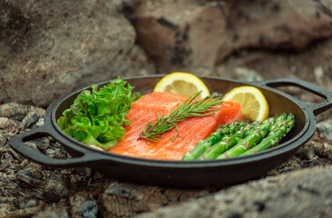 Healthy baked salmon steaks with greens and asparagus in a black cast iron skillet. A delicious low-carb breakfast.